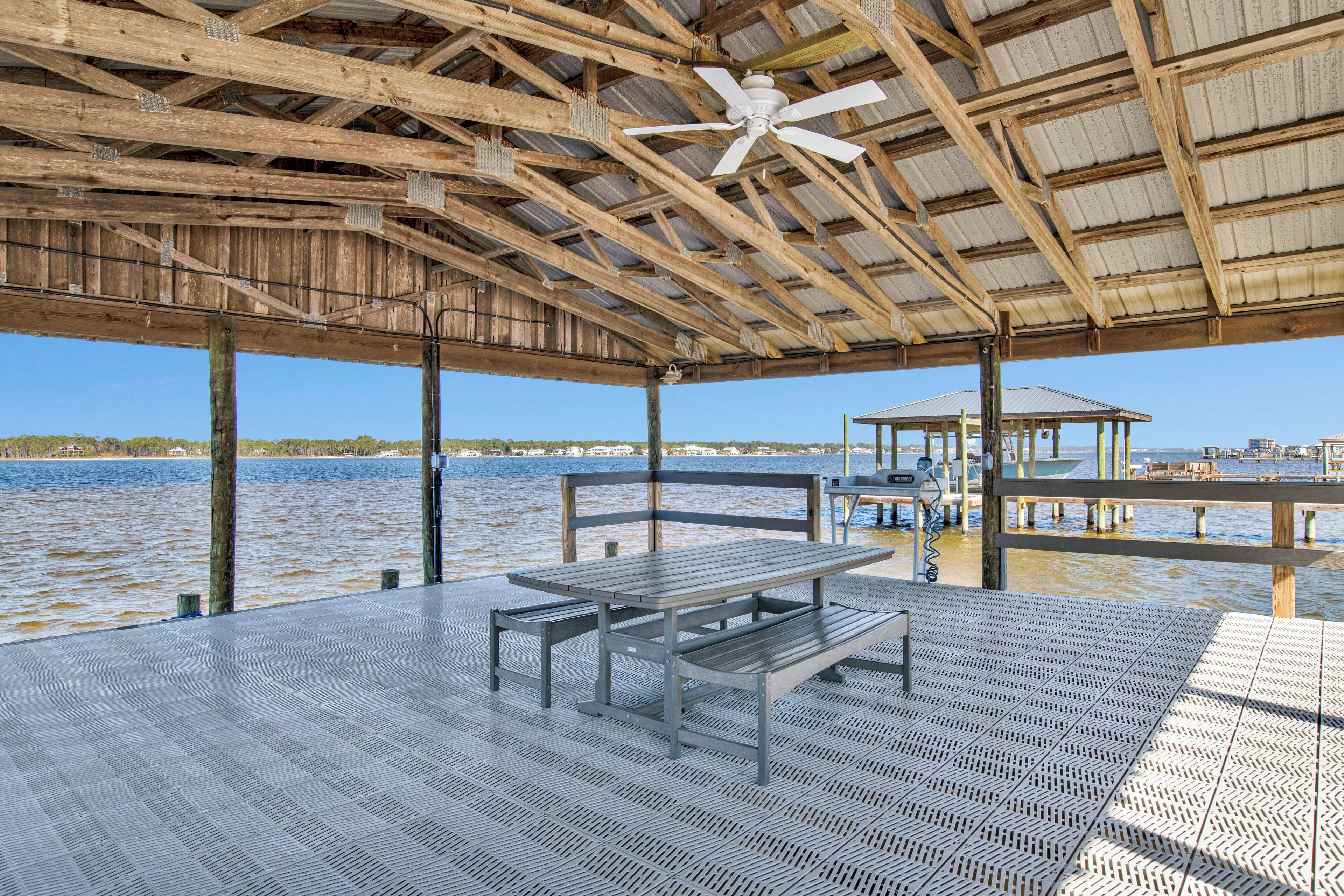 Un espacio al aire libre cubierto con una mesa y bancos, con vistas a un cuerpo de agua.