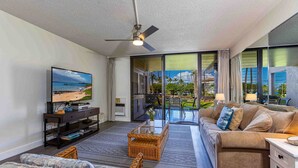 A modern living room with a television, sofa, and wicker furniture. - Kamaole Sands #10-111  Ocean View, Inner Court, Ground Floor, Close to Beach (Kihei)