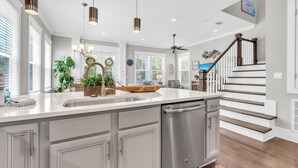 Een moderne keuken met een groot kookeiland, een roestvrijstalen vaatwasser en een houten kom als decoratie.