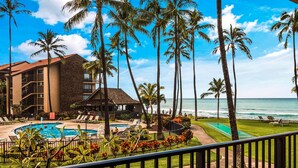 Um resort com piscina, palmeiras e vista para o oceano.