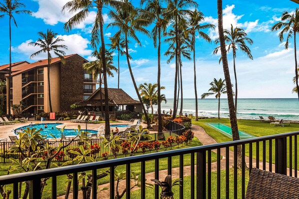 A resort with a swimming pool, palm trees, and a view of the ocean.