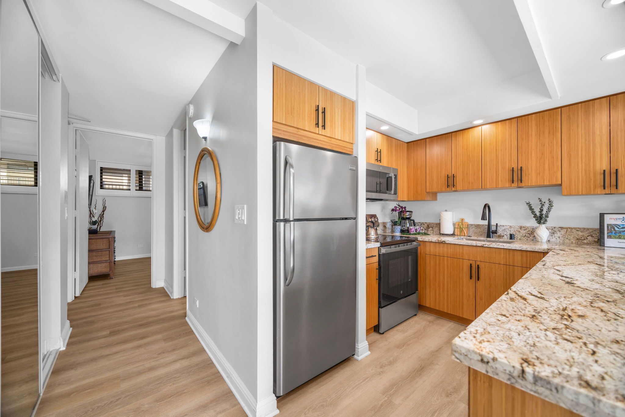 A modern kitchen with wooden cabinets, stainless steel appliances, and a granite countertop.