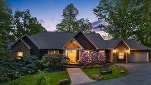 Une maison à deux étages avec une façade en pierre, un porche à l’avant et un garage.