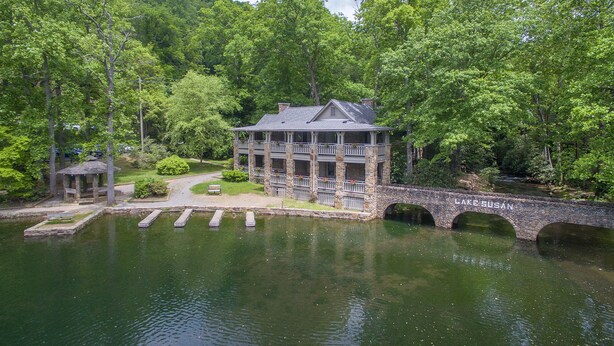 Eine Steinsbrücke über einem See, mit einem zweistöckigen Steinhaus auf der rechten Seite.