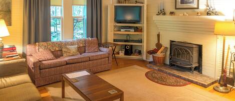 Una sala acogedora con sofá, mesa de centro, chimenea y televisor.