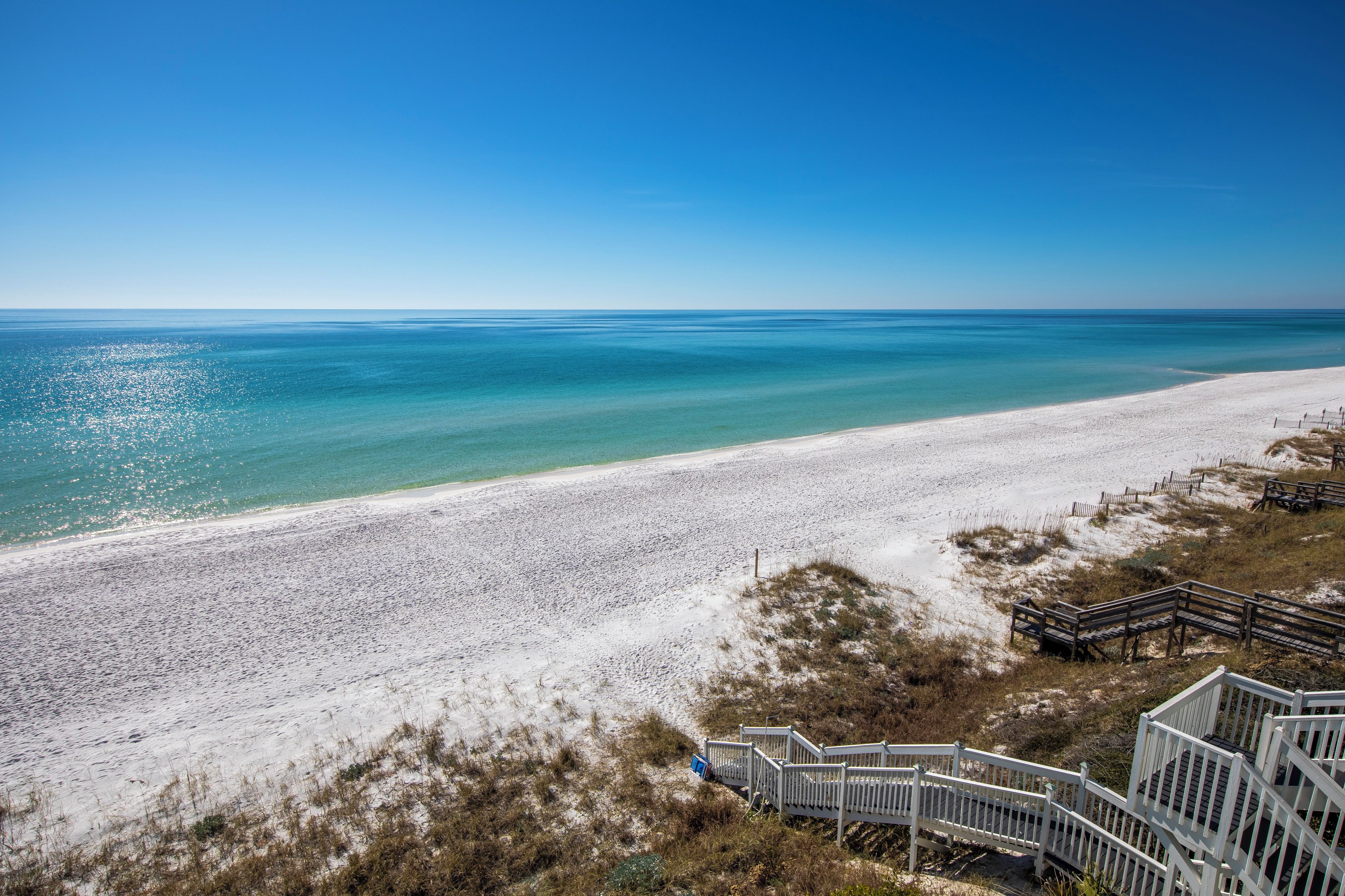 A beach with a wooden boardwalk leading to a sandy shore.