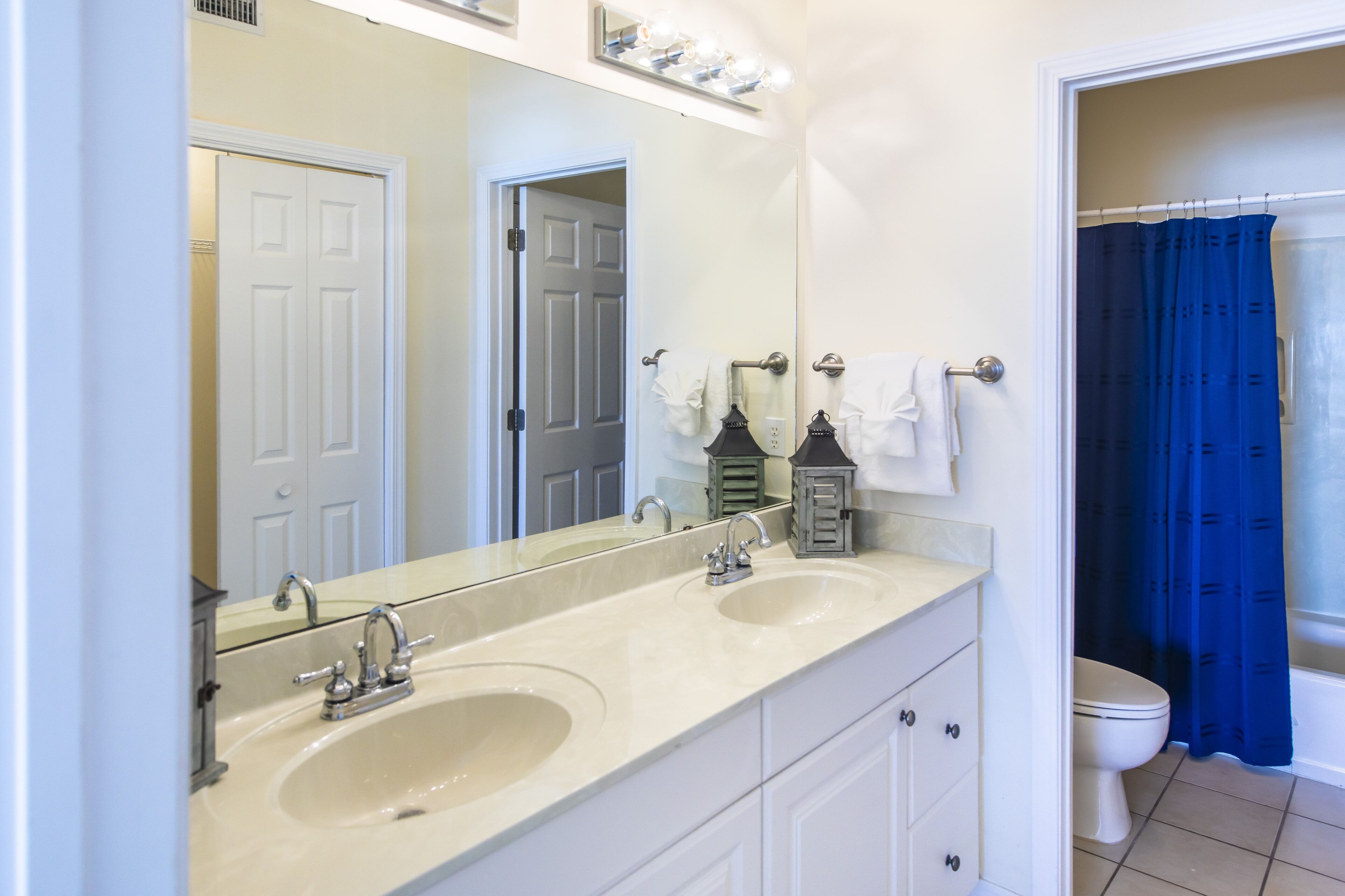 A bathroom with two sinks, a mirror, and a toilet.