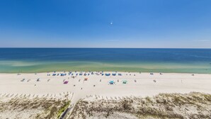 Una playa con numerosos paraguas y sillas de playa, un cielo despejado y un mar tranquilo.