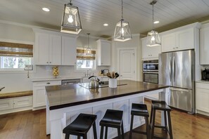 Una cocina moderna con armarios blancos, electrodomésticos de acero inoxidable y una isla grande con taburetes de bar.