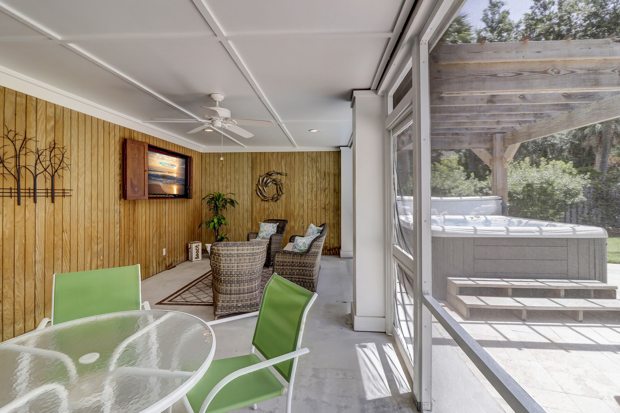 A modern outdoor seating area with wicker furniture, a glass table, and a ceiling fan.