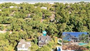 Vista aérea de una zona residencial con casas rodeadas de vegetación densa, una playa al fondo y una piscina visible.