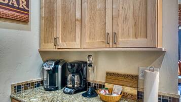 A kitchen with wooden cabinets, a coffee maker, a basket, and a paper towel holder.
