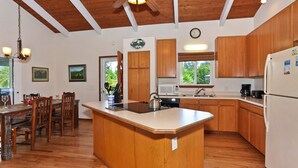 Una cocina con armarios de madera, una isla central, un microondas y un refrigerador.