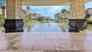 A hotel lobby with a central water feature, stone columns, and surrounding greenery.