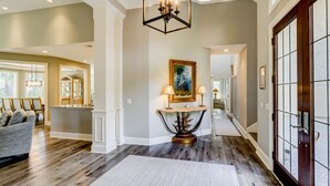 A spacious hallway with a wooden floor, a central console table with lamps, and a framed painting on the wall. - 37 St. George - 5 minute walk to the beach! (Hilton Head Island)