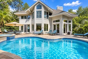 Ein zweistöckiges Haus mit Swimmingpool, Gartenmöbeln und einer Terrassenanlage.