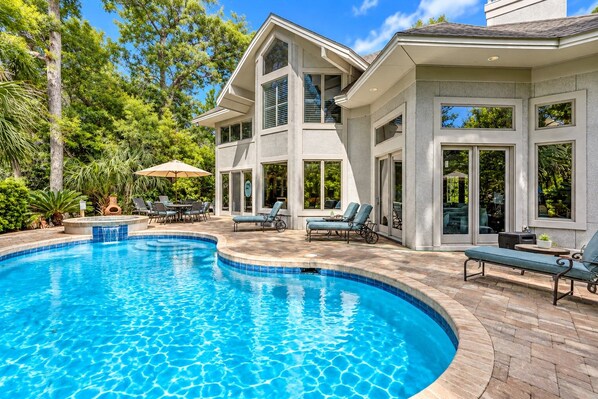 A residential property with a swimming pool, outdoor furniture, and a patio area.