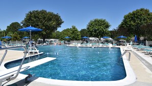 Une piscine rectangulaire avec plusieurs couloirs de nage, entourée de chaises longues et de parasols bleus.