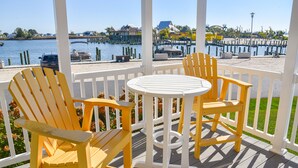 Une terrasse en bois avec deux chaises Adirondack jaunes et une petite table ronde.