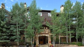 A lodge with a stone facade, wooden balconies, and a welcoming entrance. - Amazing Arrowhead condo, POOL is OPEN! Walk to slopes, ski locker!! (Edwards)