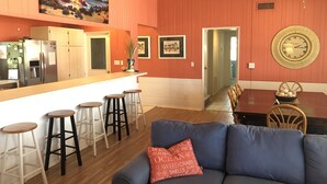 Een moderne keuken met een groot eiland, barkrukken en een eethoek met een houten tafel en stoelen.