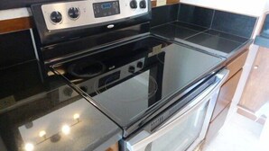 A kitchen with a black stove, oven, and a black countertop.