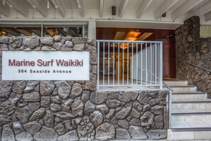Un muro de piedra con un letrero de Marine Surf Waikiki en el número 364 de Seaside Avenue.