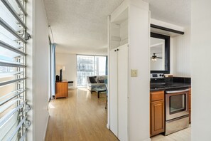 A modern kitchen with a built-in oven and a dining area with a table and chairs. - Located in the Heart of Waikiki!  Free parking & W/D in the unit! (Honolulu)