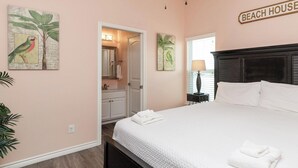 A bedroom with a bed, a ceiling fan, a nightstand, a lamp, and a sign that reads "BEACH HOUSE". - Pet-Friendly Beach Escape | Pool Access & Walk to Beach (Corpus Christi)