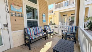 A covered outdoor seating area with a sofa and chairs, a small table, and a door with a keypad lock. - Pet-Friendly Beach Escape | Pool Access & Walk to Beach (Corpus Christi)