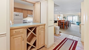 Una cocina moderna con armarios de madera, una cava empotrada y una zona de comedor con mesa y sillas.