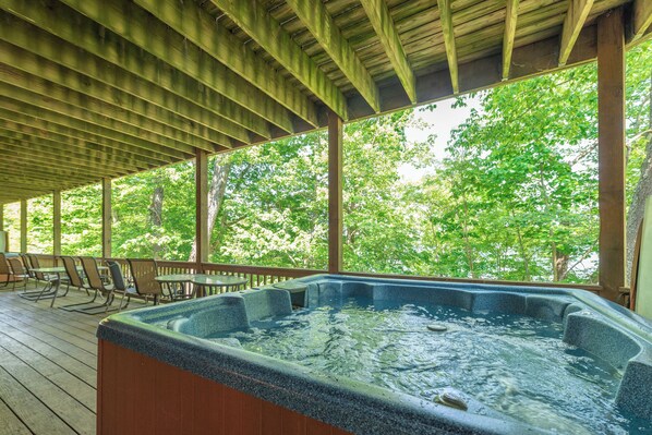 A hot tub area with a wooden deck, chairs, and a view of trees. - Tranquil Lakefront w/ Twin Hot Tubs & Dock (Oakland)