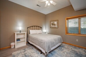 A bedroom with a bed, two bedside tables with lamps, a window with blinds, and a ceiling fan. - Tranquil Lakefront w/ Twin Hot Tubs & Dock (Oakland)