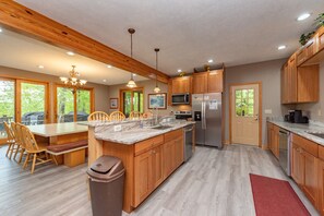 Enjoy cooking in this well-equipped kitchen with a large island, stainless steel appliances, and a dining area with a table and chairs.