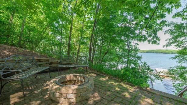 A stone fire pit surrounded by a stone bench area overlooking a lake. - Tranquil Lakefront w/ Twin Hot Tubs & Dock (Oakland)