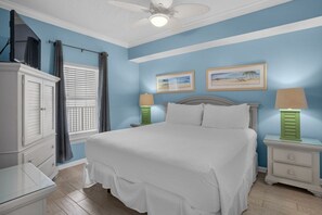 A bedroom with a bed, nightstands, a dresser, and a ceiling fan.