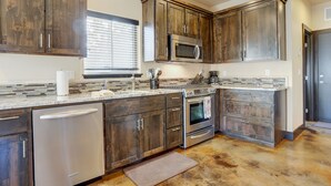 Una cocina con armarios de madera oscura, electrodomésticos de acero inoxidable y salpicadero de azulejos.