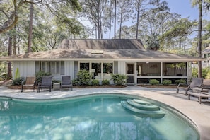 A house with a swimming pool, a covered porch, and a garden.