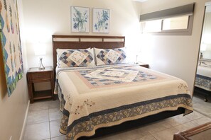 A bedroom with a bed, two nightstands, a mirror, and a window.