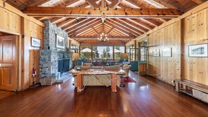 A spacious wooden interior with a stone fireplace, wooden beams, and a large sofa.