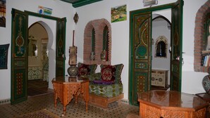 A traditional room with a wooden sofa, a small table, and a decorative mirror.