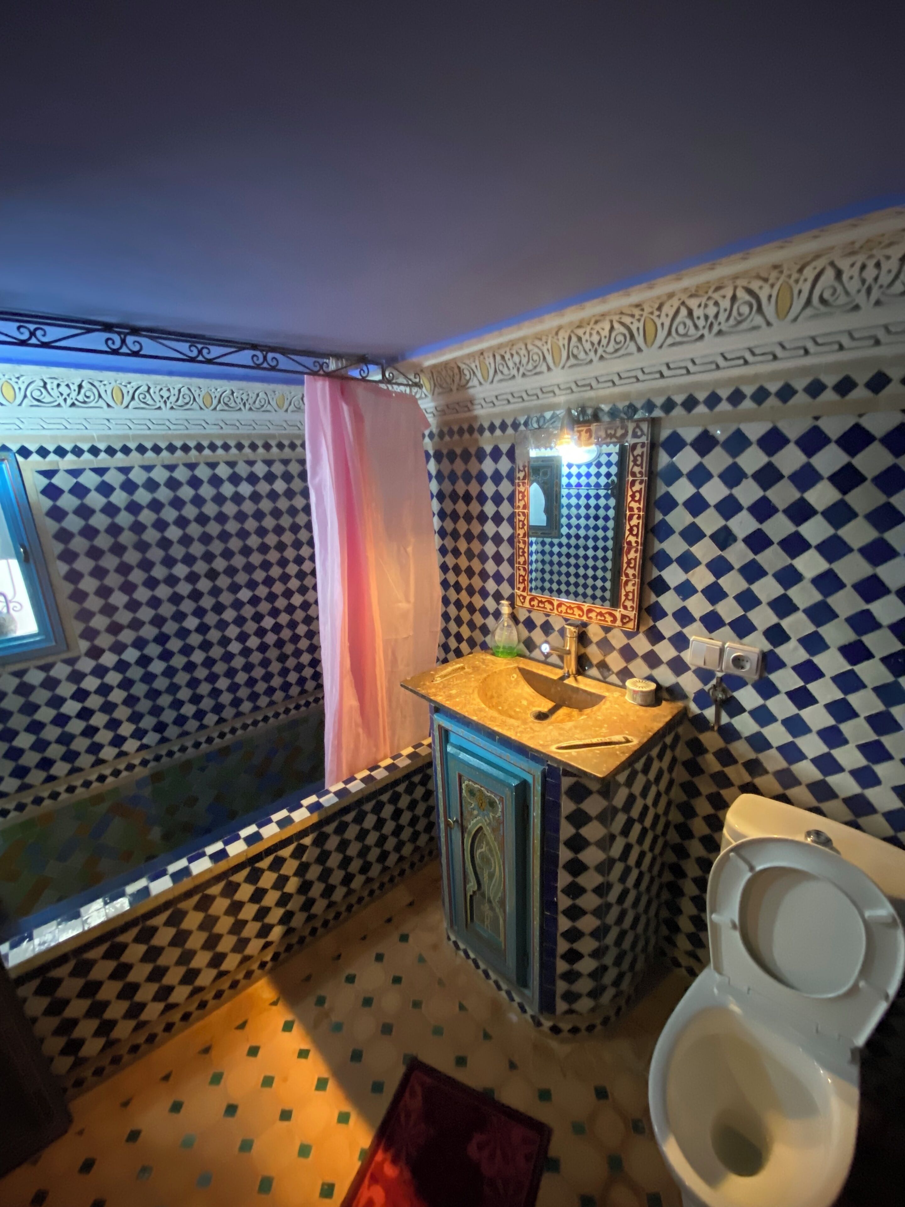 A bathroom with a checkered tile pattern, a sink with a mirror, and a toilet.