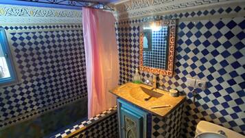 A bathroom with a checkered tile pattern, a sink with a mirror, and a toilet.