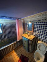 A bathroom with a checkered tile pattern, a sink with a mirror, and a toilet.