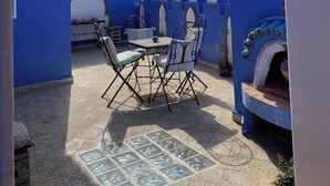 A patio with a table and chairs, a tiled floor, and a view of mountains.