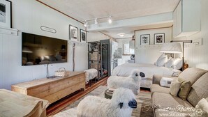 Ein gemütliches Zimmer mit einem Bett, einer Couch, einer Holzkommode und einem an der Wand befestigten Fernseher.