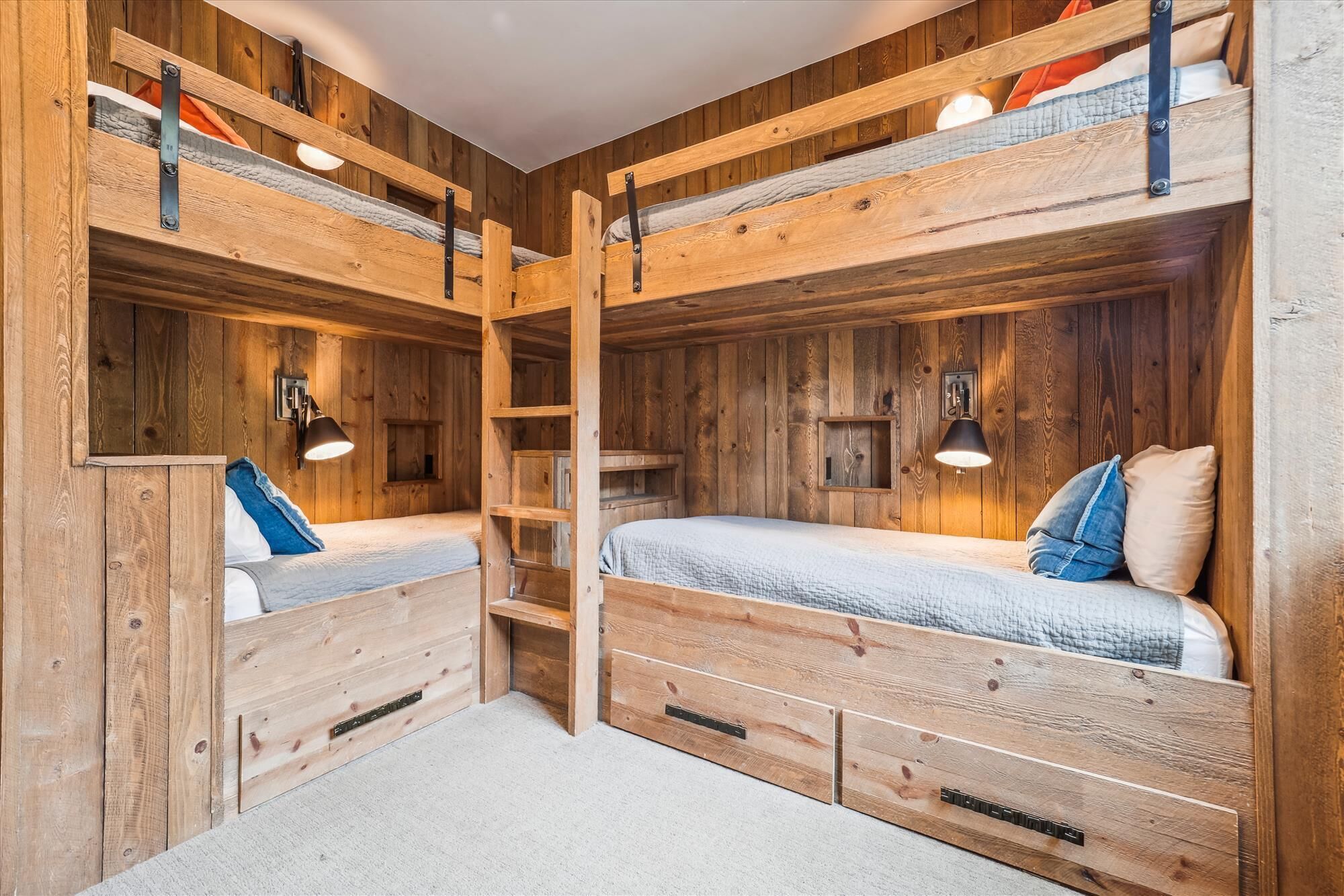 Une chambre avec deux lits superposés, des murs en bois et des étagères intégrées.