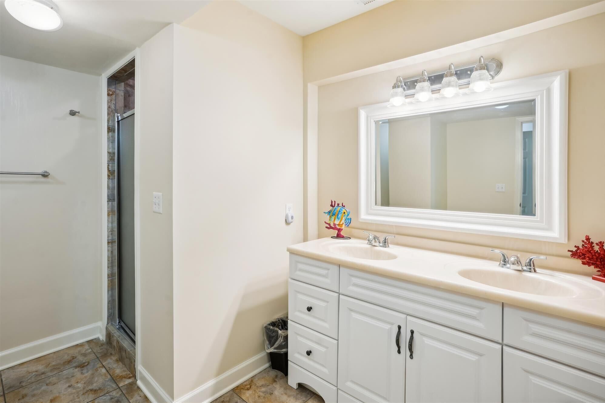 A bathroom with two sinks, a large mirror, and a shower.