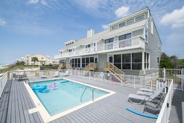 A pool area with a view of the ocean, deck chairs, and a building with multiple balconies. - Dune I Townhomes #12 - Beachside Pool, Private Beach Boardwalk, Dune Allen Beach (Santa Rosa Beach)