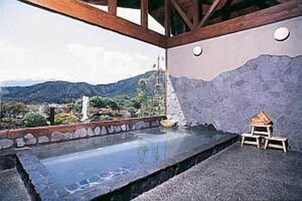 Un área de baños termales con vistas a montañas y follaje verde.